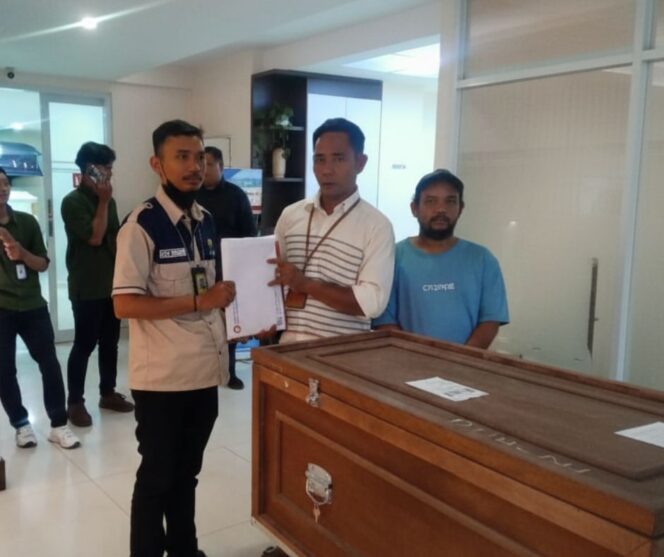 
					Suwandi menerima jenazah Siti Muiah dari staf BP3MI Serang di Terminal Cargo